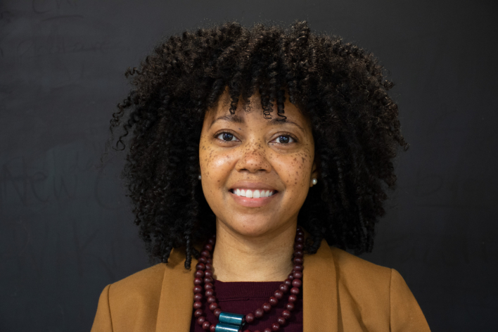 Lona Vincent wearing a tan coat and burgundy top, smiling at the camera.