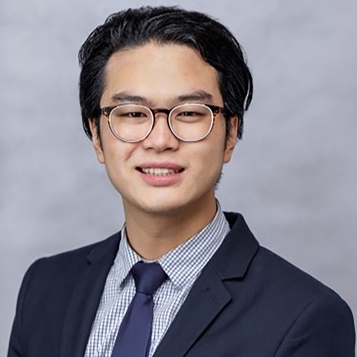 An image of an Asian man wearing glasses and a suit smiling at the camera.