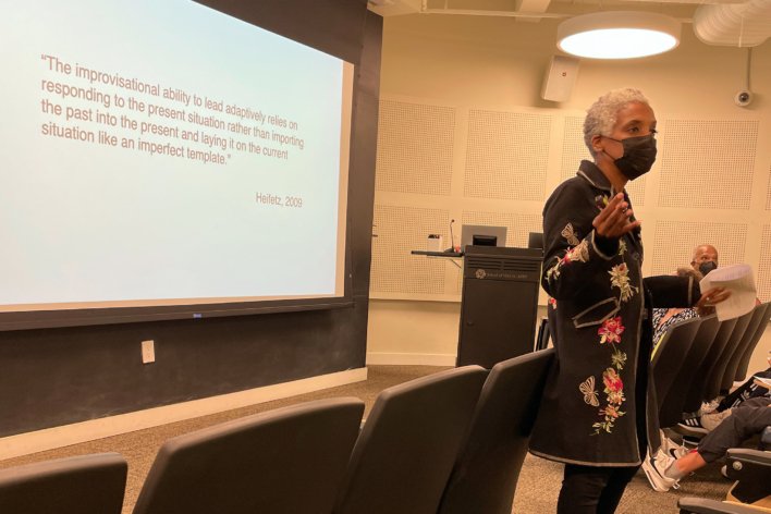 Karen Proctor speaking in front of a quote by Heifetz, 2009 on Adaptive Leadership.