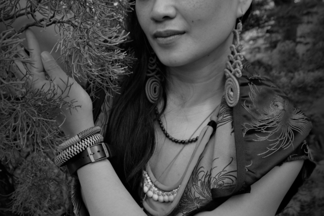 A black and white headshot of Kimberly Tate posing close to some trees in a wooded area.