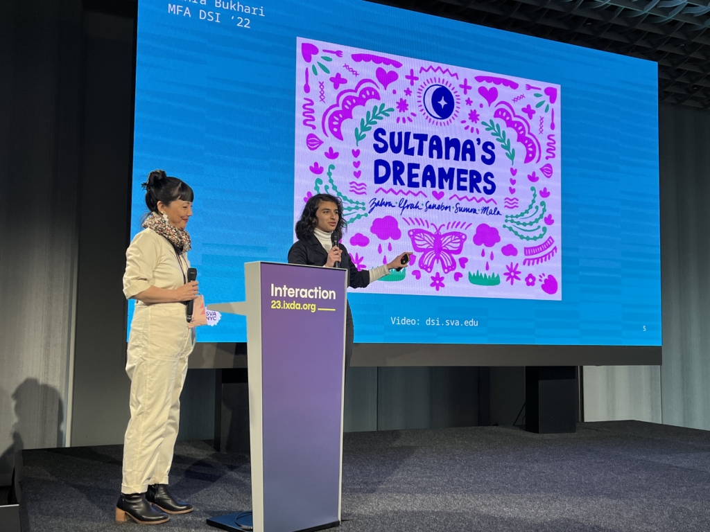 Zahra Bukhari and Miya Osaki standing on stage, giving a presentation entitled "Sultana's Dreamers"