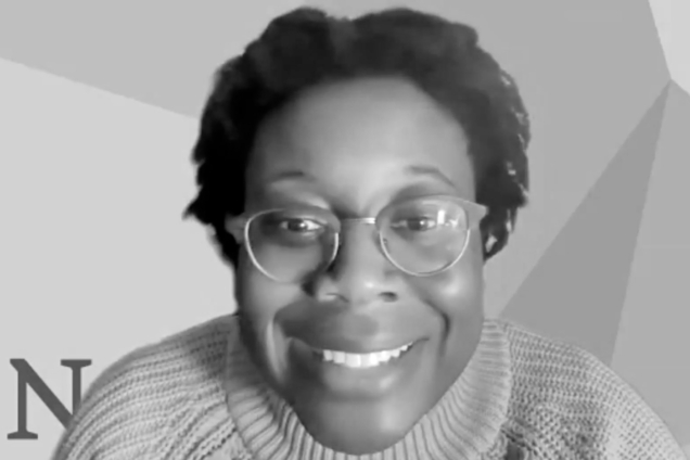 A black and white screen-captured image of a Black woman smiling at the camera.