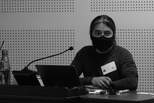 A man wearing a face mask standing at a podium.