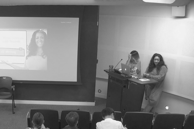 A black and white image of two women standing at a podium giving a presentation.