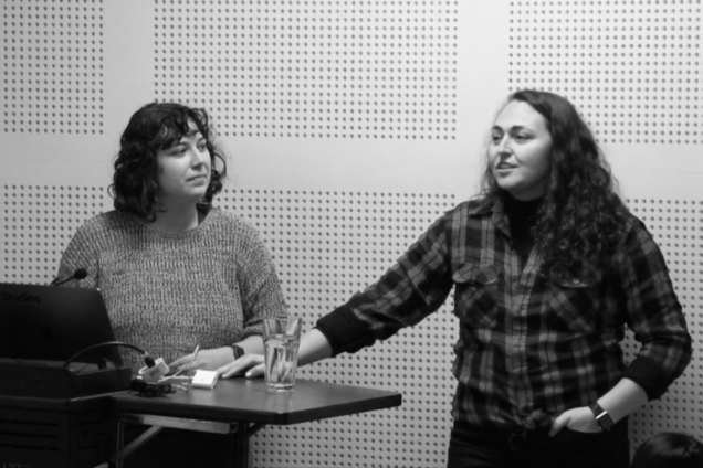 A black and white image of two women standing at a podium giving a presentation.