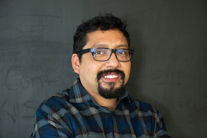 A man wearing a plaid shirt and glasses, smiling for the camera.
