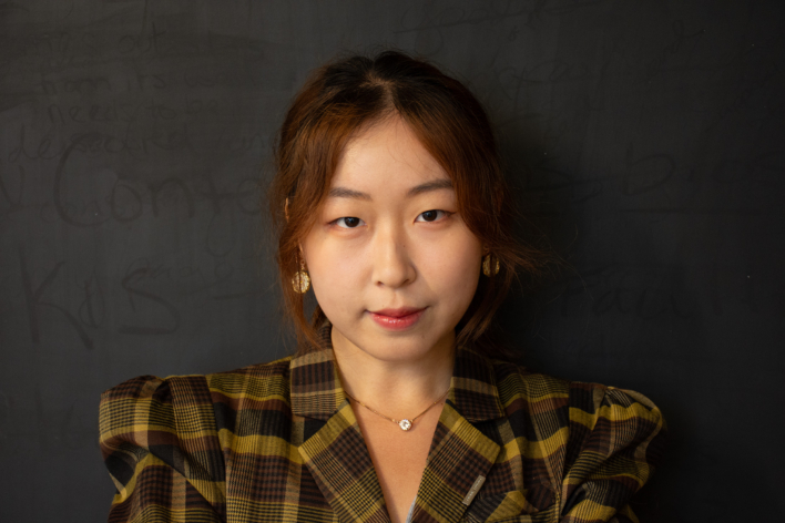 An Asian woman wearing a plaid jacket, posing for the camera.