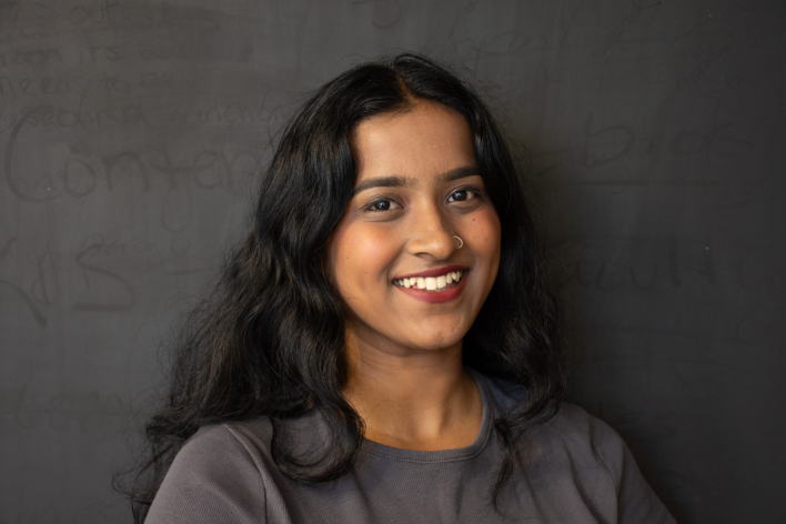 A brown-skinned woman smiling at the camera.
