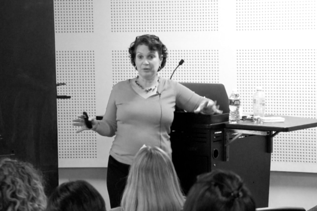 A woman with curly, dark hair giving a presentation.