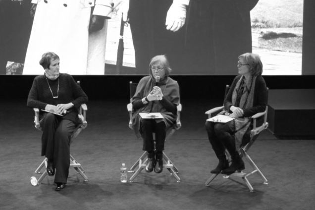 Three women sitting on a stage giving a presentation.