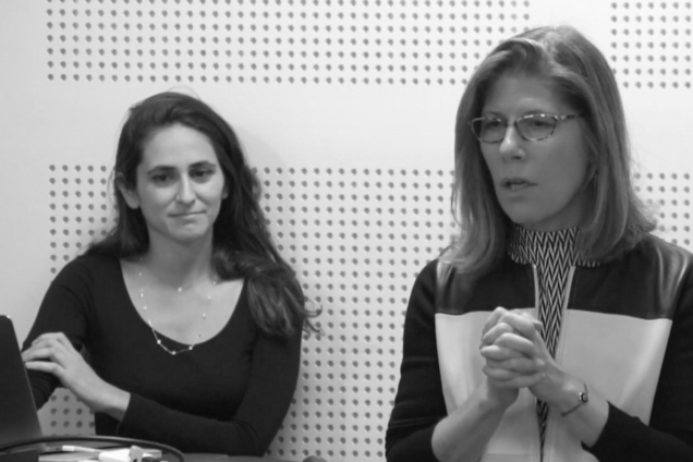 Two white women standing at a podium giving a presentation.