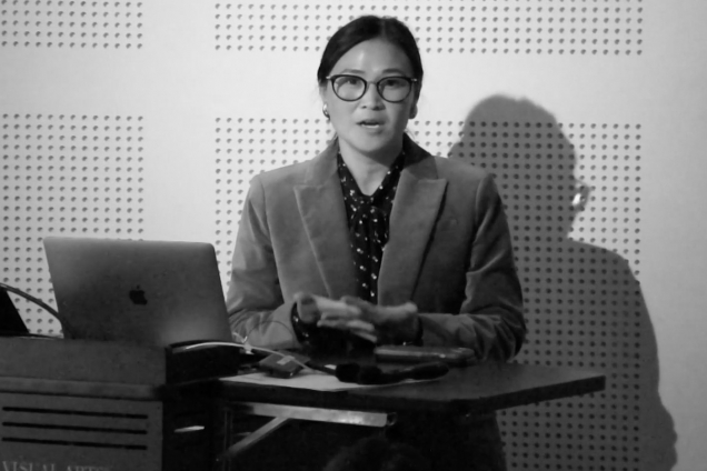 An asian woman with a suit on lecturing