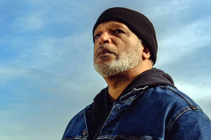 David Proctor staring off against a blue sky with streaks of clouds.