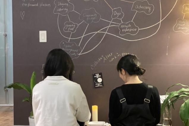 Two students with black hair, one is wearing white and the other black, sitting in front an altar.