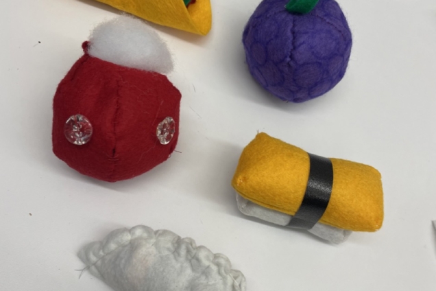 Collection of felted foods including a taco, plumb, tamago sushi, dumpling and tomato