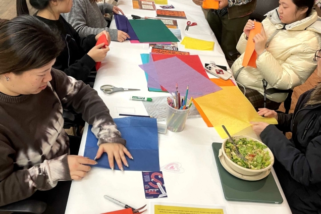 Students and Ishan Khosla working together at a table with brightly colored tissue paper.