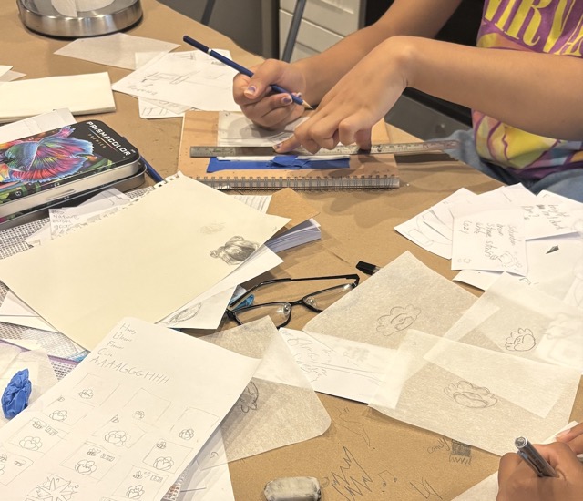 Hands holding a ruler and pencil on a table filled with small pieces of transparent paper for an animation.