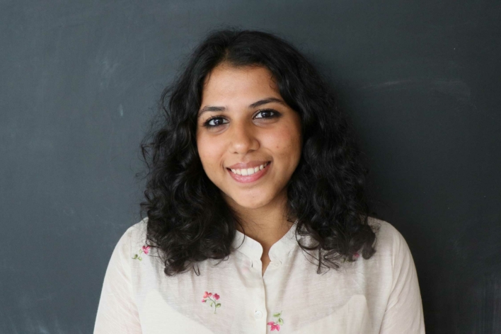 DSI student with dark curly hair and a light tan blouse.